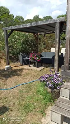 a wooden pergola with a bench and flowers at Petit chalet in Pianottoli-Caldarello