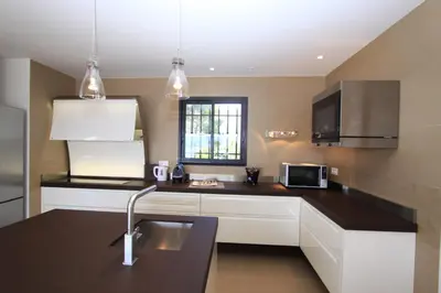 a kitchen with white cabinets and a black counter top at Résidence Affasciata in Porto-Vecchio
