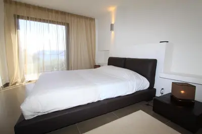 a bedroom with a bed with white sheets and a window at Résidence Affasciata in Porto-Vecchio