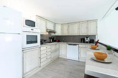 a kitchen with white cabinets and white appliances at L'Ornano - Maison climatisée avec piscine in Grosseto-Prugna
