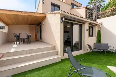a patio with chairs and a table and grass at L'Ornano - Maison climatisée avec piscine in Grosseto-Prugna
