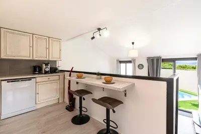 a kitchen with a white counter and stools in it at L'Ornano - Maison climatisée avec piscine in Grosseto-Prugna