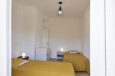 two beds in a small room with yellow sheets at Villa Jeanne in Linguizzetta
