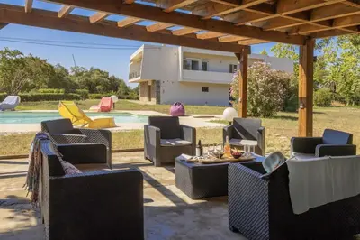 a patio with chairs and a table and a pool at Villa Jeanne in Linguizzetta