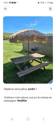 a picnic table with a straw umbrella on the grass at Rez de villa avec jardin in Porto-Vecchio