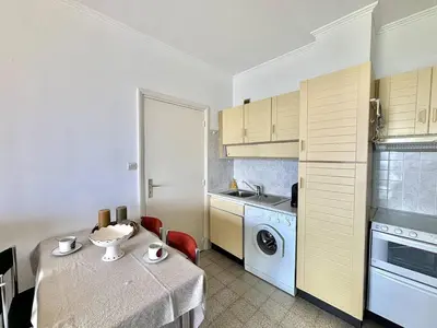 a small kitchen with a table and a washing machine at Appartement 2 pièces Le Versailles Ajaccio Sanguinaires in Ajaccio