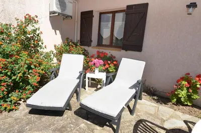 three white chairs sitting in front of a building with flowers at Corsicadream cupabia, appartement dans villa proche Porticcio, vue mer, piscine in Pietrosella