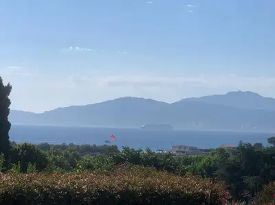 a red kite flying in the sky over a field at Corsicadream cupabia, appartement dans villa proche Porticcio, vue mer, piscine in Pietrosella