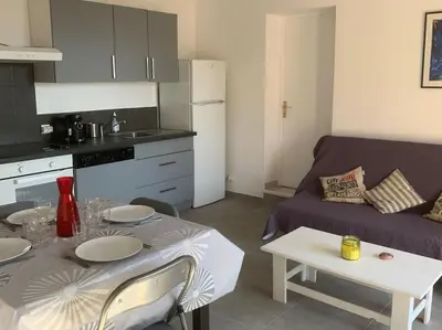 a kitchen and a living room with a table and a couch at Corsicadream cupabia, appartement dans villa proche Porticcio, vue mer, piscine in Pietrosella
