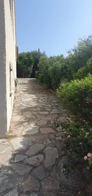 a stone walkway next to a building at Appt cosy rez de villa in Furiani