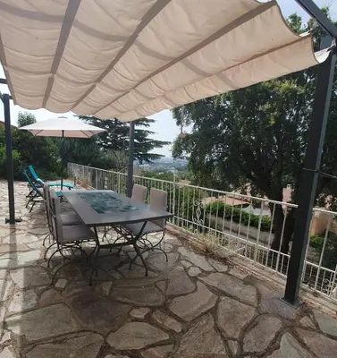 a patio with a table and chairs under an umbrella at Appt cosy rez de villa in Furiani