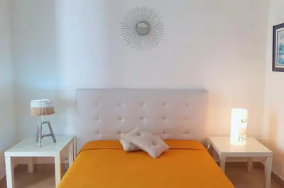 a bedroom with a bed and two tables and a mirror at Villa U Rustincu Vue mer Acces plage Ruppione Pietrosella in Pietrosella