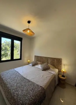 a bedroom with a large bed with two lamps at Appartement paisible au cœur des oliviers, à deux pas de Bonifacio in Bonifacio