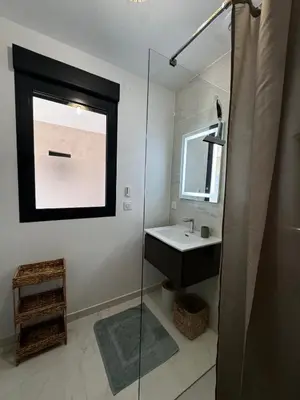 a bathroom with a sink and a glass shower at Appartement paisible au cœur des oliviers, à deux pas de Bonifacio in Bonifacio