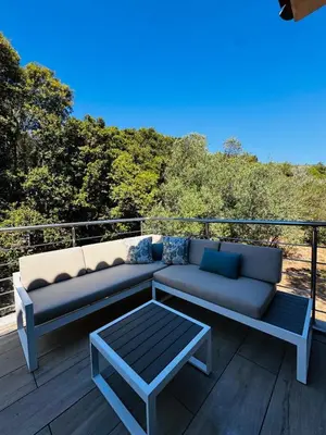 a couch and a coffee table on a deck at Appartement paisible au cœur des oliviers, à deux pas de Bonifacio in Bonifacio