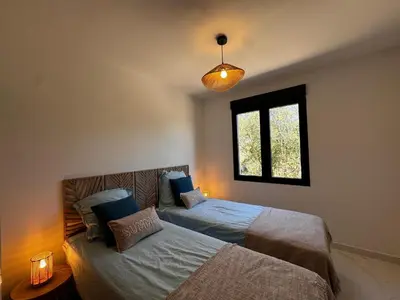 a bedroom with two beds and a window at Appartement paisible au cœur des oliviers, à deux pas de Bonifacio in Bonifacio