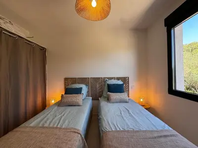 a bedroom with two beds and a window at Appartement paisible au cœur des oliviers, à deux pas de Bonifacio in Bonifacio