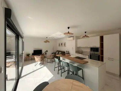 a kitchen and living room with a table and chairs at Appartement paisible au cœur des oliviers, à deux pas de Bonifacio in Bonifacio