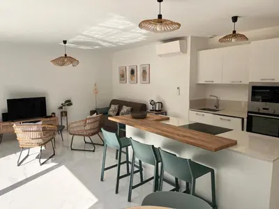 a kitchen and living room with a table and chairs at Appartement paisible au cœur des oliviers, à deux pas de Bonifacio in Bonifacio