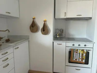 a kitchen with white cabinets and a white stove top oven at T2 ville et bord de mer in Ajaccio
