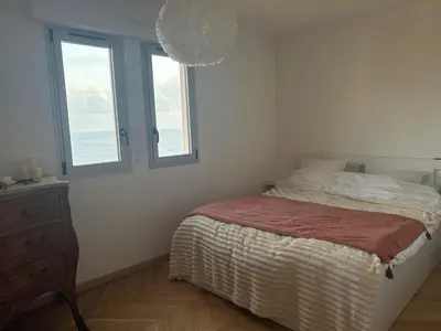 a bedroom with a bed and two windows at T2 ville et bord de mer in Ajaccio