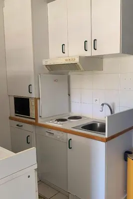 a kitchen with white cabinets and a sink at Chez Aline - Appartement en bord de mer in Cervione