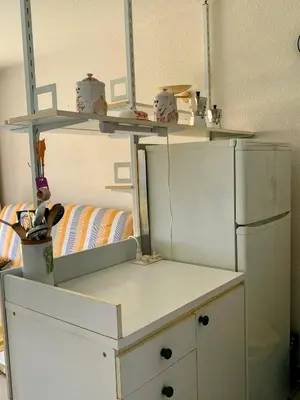 a kitchen with a white refrigerator and shelves at Chez Aline - Appartement en bord de mer in Cervione