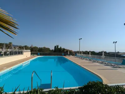 a large blue swimming pool with chaise lounge chairs at Chez Aline - Appartement en bord de mer in Cervione