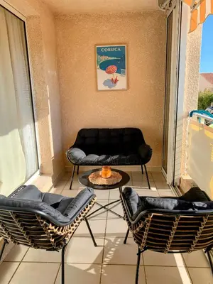 a balcony with a couch and chairs and a table at Chez Aline - Appartement en bord de mer in Cervione