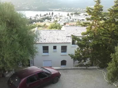 a red car parked in front of a white house at Villa vue mer 400m plages et commerces calme confort pour 6 à 8 personnes soins de remise en forme possible in Propriano