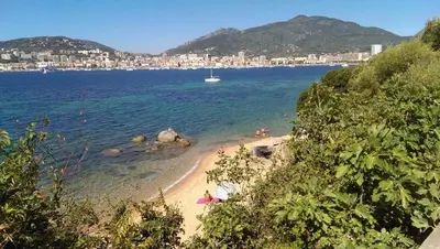 a beach with people on it with a boat in the water at Jardin-Marin-Ajaccio in Ajaccio