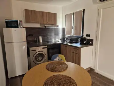 a small kitchen with a table and a refrigerator at Agréable studio in Afa