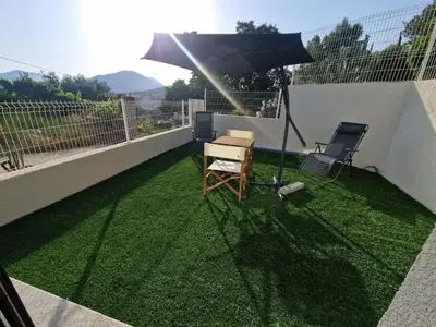 an umbrella and a desk and a chair on a balcony at Agréable studio in Afa