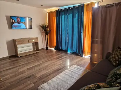 a living room with a couch and a flat screen tv at Agréable studio in Afa