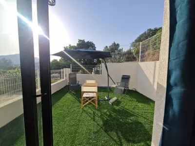 a balcony with an umbrella and a table and chairs at Agréable studio in Afa