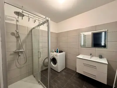 a bathroom with a shower and a washing machine at Charmant 2 pièce tout équipé climatisé in Sainte-Lucie de Porto-Vecchio