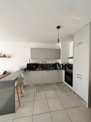 a kitchen with white cabinets and a tile floor at Charmant 2 pièce tout équipé climatisé in Sainte-Lucie de Porto-Vecchio