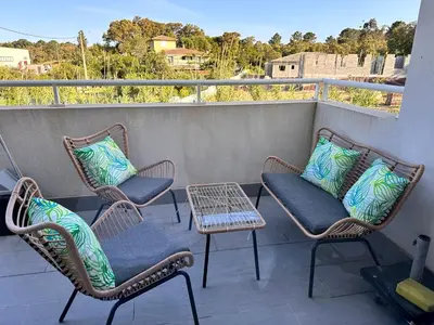 three chairs and a table on a balcony at Charmant 2 pièce tout équipé climatisé in Sainte-Lucie de Porto-Vecchio