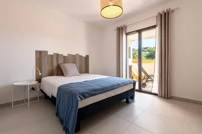 a bedroom with a bed and a sliding glass door at A Nepita - 150m de la plage in Pietrosella