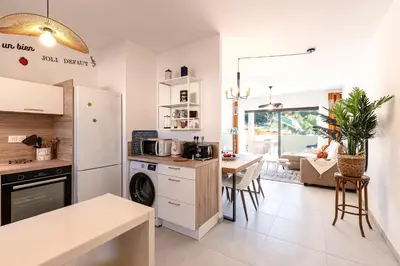 a kitchen with a white refrigerator and a table at A Nepita - 150m de la plage in Pietrosella