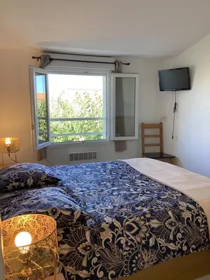 a bedroom with a bed with a blue comforter and a window at La BénéCIOLA, vue Mer, Box Fibre SFR, High Speed Internet in Cervione
