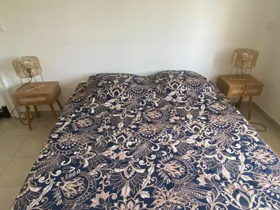 a bed with a blue and white comforter and two night stands at La BénéCIOLA, vue Mer, Box Fibre SFR, High Speed Internet in Cervione
