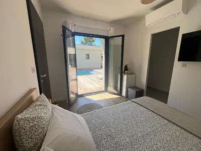 a bedroom with a bed and a sliding glass door at A Felicità in Sainte-Lucie de Porto-Vecchio