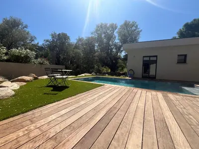 a pool with a wooden deck next to a house at A Felicità in Sainte-Lucie de Porto-Vecchio