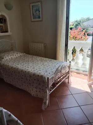 a bed in a bedroom with a view of a balcony at Maison des pruniers in Furiani