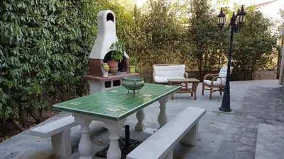 a table with a bench and a lamp on a patio at Maison des pruniers in Furiani