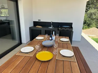 a wooden table with plates and wine glasses on it at Villa Bavella in Zonza