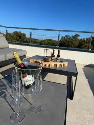 a table with wine bottles and glasses on a balcony at Villa Bavella in Zonza