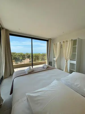 a bedroom with a large bed with a large window at Casa Vitalba in Zonza