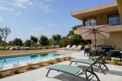 a patio with chairs and an umbrella next to a pool at Casa Vitalba in Zonza